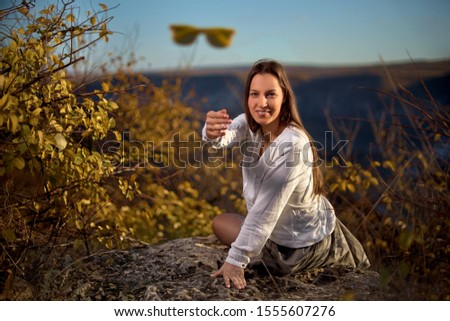 Cute girl throws glasses sitting on a mountain and enjoys the beautiful hills of the mountains on a sunny day