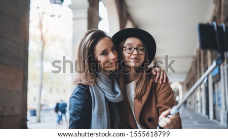 two girlfriends taking photo selfie on smartphone mobile in city. Blogger hipster travels in Barcelona. Holiday friendship concept. Travelers self cellphone internet technology mockup space