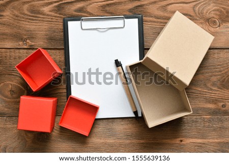Postal cardboard boxes and blank page document with a pen on the brown table background.