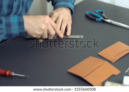 a tanner on a black table makes an accessory from genuine brown leather. leather business concept.