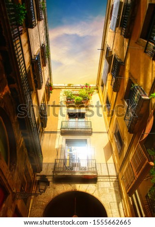 passageway in the narrow streets of Barcelona near La Rambla street showing window glowing in sunset light