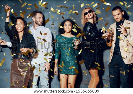 Happy young people dancing and having fun with confetti flying everywhere. Diverse group of people enjoy party. Holidays, celebration, nightlife and celebration concept   