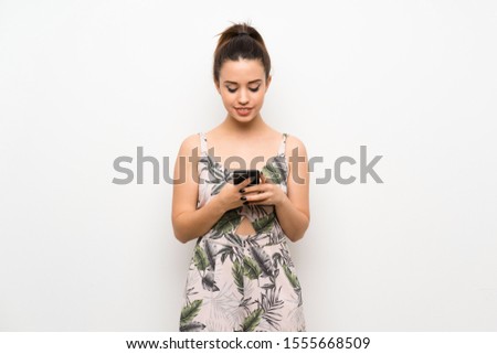 Young woman over isolated white background sending a message with the mobile