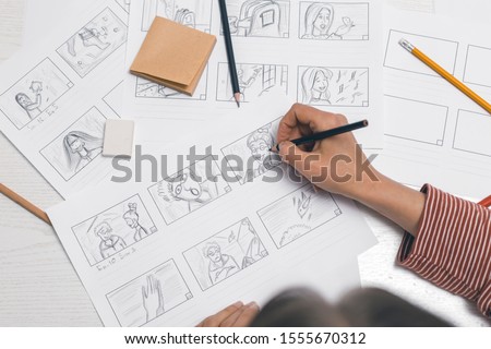 Woman's hand draws a storyboard for a film or cartoon. Royalty-Free Stock Photo #1555670312