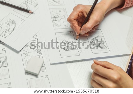 Woman's hand draws a storyboard for a film or cartoon. Royalty-Free Stock Photo #1555670318