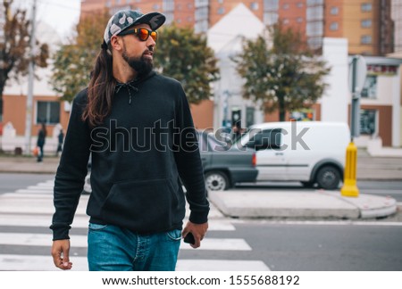 City portrait of handsome hipster guy with beard wearing black blank hoodie or hoody with space for your logo or design. Mockup for print