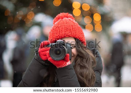 woman photographer with professional camera shooting outdoors at winter time