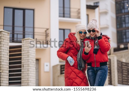 Mother and daughter doing selfie outside in winter