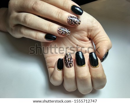 Black leopard print manicure on young hands of beautiful girl.