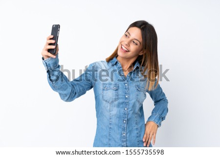 Young woman over isolated white background making a selfie