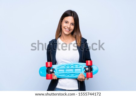 Young woman over isolated blue background with skate