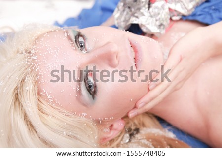 Beautiful blonde caucasian woman in blue dress on Christmas background with snow
