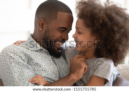 Close up of loving african American young dad and cute little daughter have fun play together at home, smiling biracial father tickle laugh enjoy close moment with small girl child, bonding concept