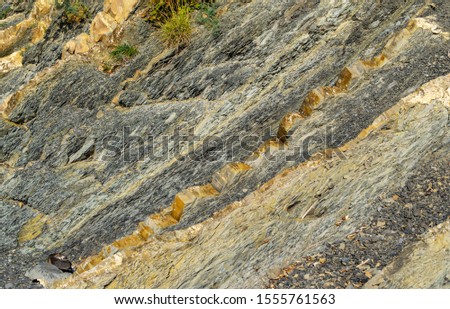 Striped natural texture of stones and rock fragments on Caucasus mountains on Black Sea coast in Olginka as original texture background. Brown, yellow, gray colored stone. Nature concept for design