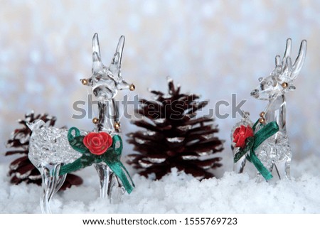 Glass Reindeer on Snow with pine cones. Holiday Christmas theme with festive background.