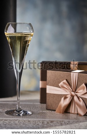 Champagne color image of gift boxes with bronze ribbons and a glass of champagne.