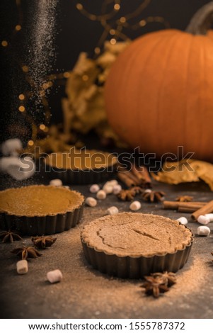 pumpkin homemade vegan pie and spices cinnamon, anis, orange  pumpkins with yelllow dry autumn leaves decor on dark table background.Harvesting,autumn and Thanksgiving concept