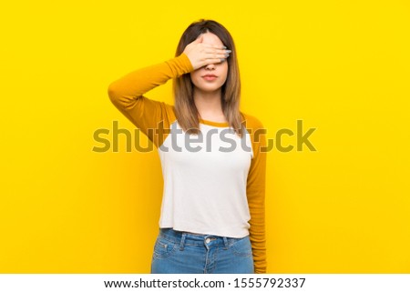 Pretty young woman over isolated yellow wall covering eyes by hands. Do not want to see something