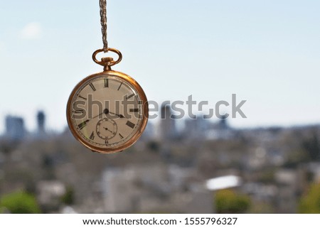Gold watch hanging in the background you can get to see a city out of focus. Retro concept.