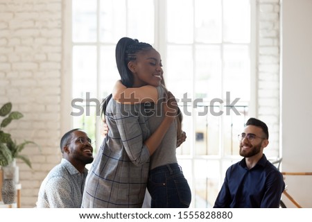 Different ethnicity people gathered together in rehab center try overcome addiction or mental problems, african woman psychologist counsellor hugging girl supporting her, group therapy session concept Royalty-Free Stock Photo #1555828880