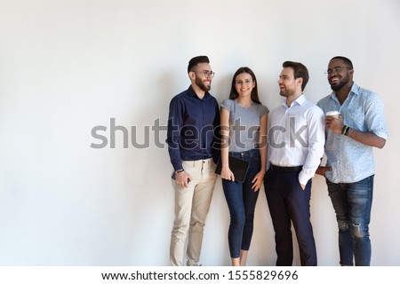 Four diverse young business people pose near grey white wall studio background copy space for ad text, millennial generation arab african european professionals, human resources, new workforce concept Royalty-Free Stock Photo #1555829696