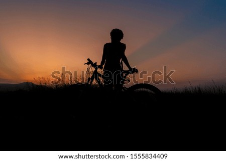 A woman riding a bicycle silhouette At the sunsets, relax at the end of the day