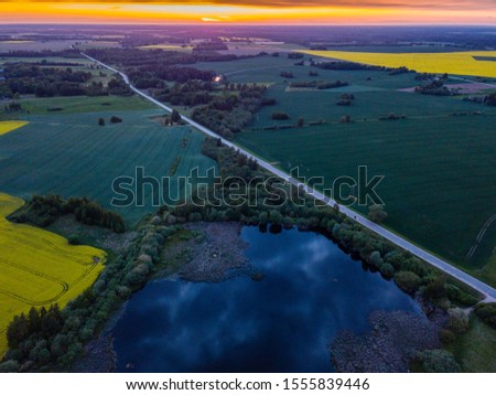 Dramatic dark clouds over the countryside landscape - Aerial photo towards sunset with the countryside road leading towards it