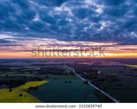 Dramatic dark clouds over the countryside landscape - Aerial photo towards sunset with the road leading to it