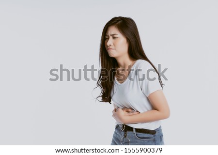 Asian woman unhappy looking sick, suffers from stomach ache stomachache isolated white background because of menstruation and eating spoiled food, Chronic gastritis. Abdomen bloating concept Royalty-Free Stock Photo #1555900379