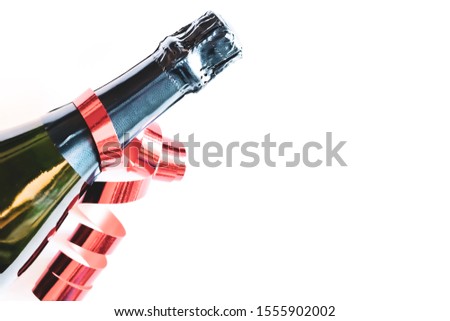 Black bottle of champagne with red ribbon on white background. Festive concept. Flat lay style. 