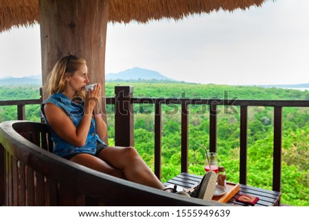Happy family travel, explore rainforest near Pemuteran. Young woman drink morning coffee and relax on lounge veranda with tropical jungle view. Walking day tour, activity in camp on summer vacation.