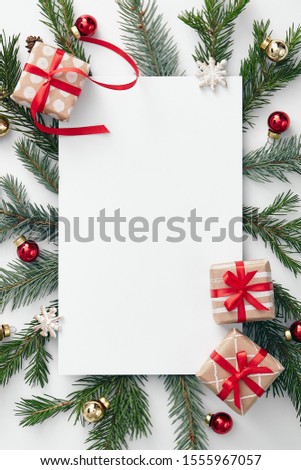 Christmas minimal concept - christmas composition with evergreen branch and xmas decoration. Rustic invitation template on white backdrop. Christmas holiday composition. Card for concept design.
