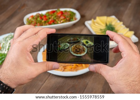 Food photography on smartphone.Mans hands make phone photography of l traditional meals. lunch or dinner.Beef stroganoff. For social media, blogging.  Top view mobile phone.