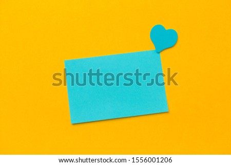 blue blank paper sheet and pink hearts on a yellow background copy space
