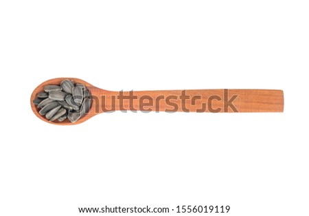 Small spoon with sunflower seeds on white background, top view