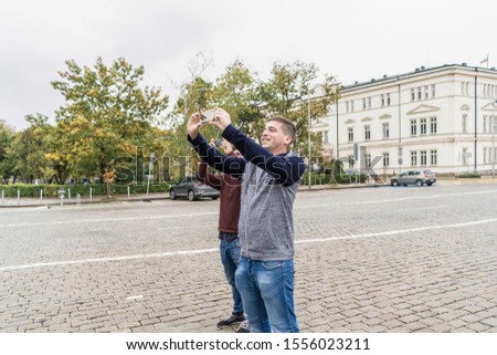 Two young tourists taking photos with their mobiles in Sofia. Bulgaria