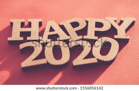 Happy 2020 background.Red wallpaper with wooden rustic style letters shot on paper backdrop,edited with fading film filter and low contrast.Winter holiday poster 