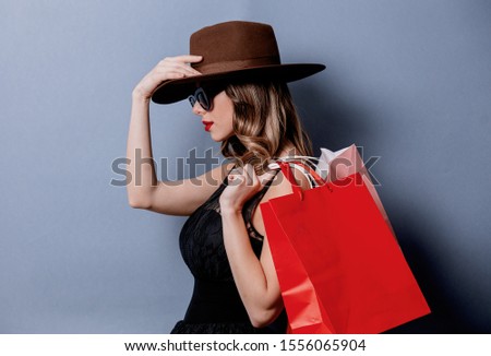Style woman in sunglasses with shopping bags on grey background