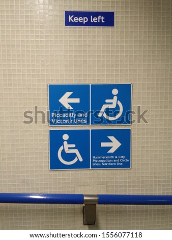 disabled access direction sign blue and white on mosaic wall