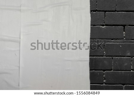 White empty creased poster paper on black urban brick wall