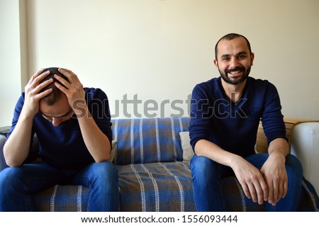 Sad and Happy (manic and depressive) Emotion of Same White Middle Aged Male Sitting on a Couch. Bipolar Man.  Royalty-Free Stock Photo #1556093444