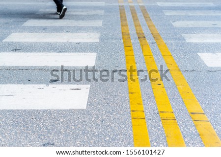 An empty crosswalk with white and yellow lines on a road, close up, outdoor