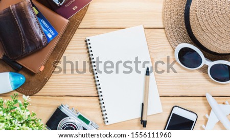 Notebook with Top view of traveler accessories,credit card,camera,smartphone and airplane on wood table top background with copy space for text.Travel new year holiday vacation concept.
