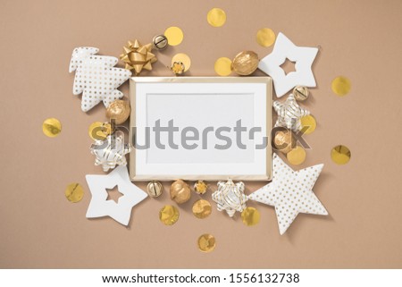 Christmas golden frame with white and golden decorations on pastel beige background. Flat lay, top view, copy space