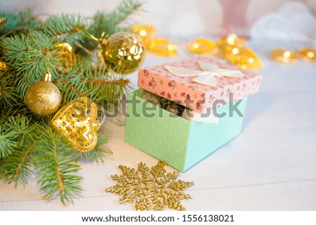 
A card with fir-tree branches with Christmas toys next to it is a gift box from which the little Rat's face looks out. Year of the Rat 2020