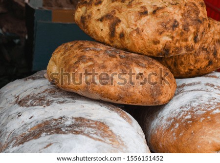 Bakery concept - gold rustic crusty loaves of bread and buns on Romanian traditional red napkin. Assortment of pastry produce. Traditional round artisan rye bread loaf gluten free healthy eating
