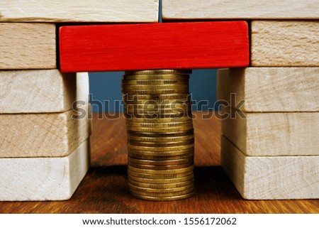 Stack of coins holds wooden blocks. Financial balance and stability.