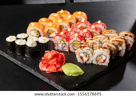 Various kinds of sushi served on black background. Sushi menu for Japanese food. Japanese sushi set. Rolls and maki with salmon, shrimp,eel, crab, caviar and avocado. Horizontal photo