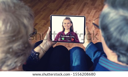 Senior couple at home holding digital tablet during video call with family doctor – virtual care remote consultation with elderly telehealth patients and medic specialist in telemedicine conversation Royalty-Free Stock Photo #1556208680