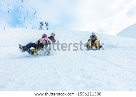 Crazy happy friends having fun with sledding on snow high mountains - Young millennial people making luge competition at white week vacation - Winter sport and travel concept - Focus on guys faces